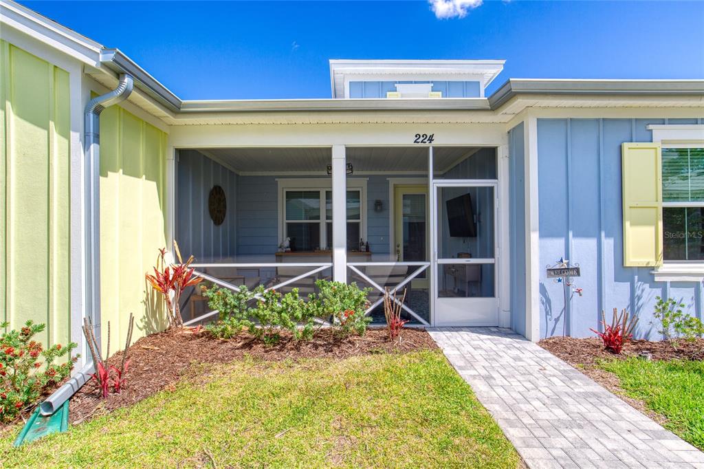 A screened-in front porch with a paved walkway leads to the entrance of a house — 224 GYPSY PALACE LANE, DAYTONA BEACH, FL