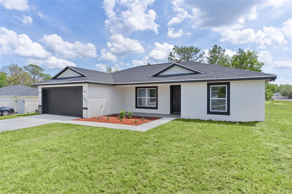 A single-story house with white stucco walls, a dark garage door, and a shingled roof — 44 MALAUKA DRIVE, OCKLAWAHA, FL