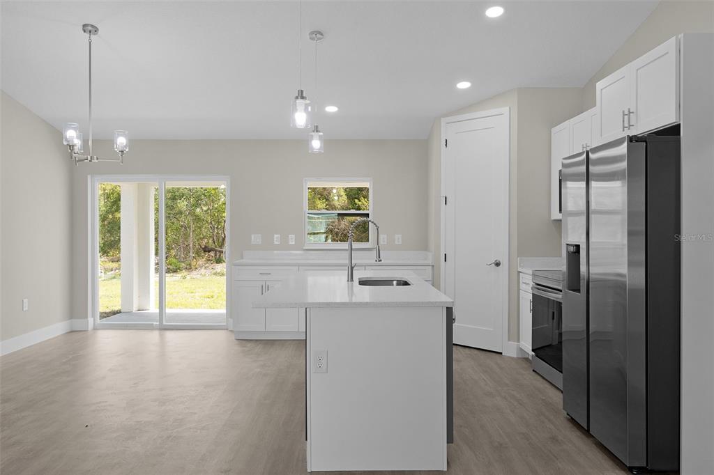 A modern kitchen features a white island, stainless steel appliances, and sliding glass patio doors — 44 MALAUKA DRIVE, OCKLAWAHA, FL