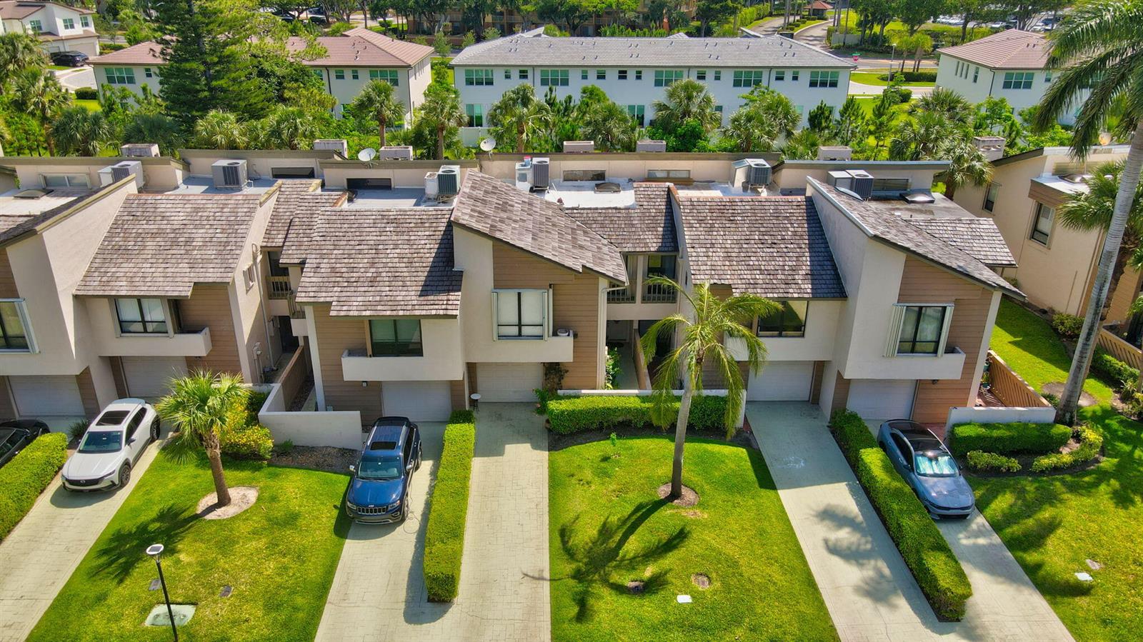 An aerial view of a multi-unit townhouse complex with driveways, green lawns, and palm trees — 22922 Ironwedge Drive, Boca Raton FL 33433, BOCA RATON, FL
