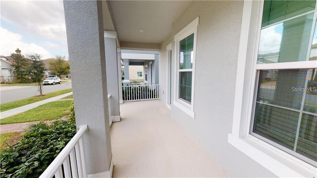 A covered front porch features a concrete floor, white railings, and a view of the street — 14704 SETON CREEK BOULEVARD, WINTER GARDEN, FL