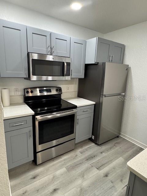 A kitchen features gray cabinets, stainless steel appliances, and light-colored countertops — 2222 SAN VITTORINO CIRCLE UNIT 105, KISSIMMEE, FL