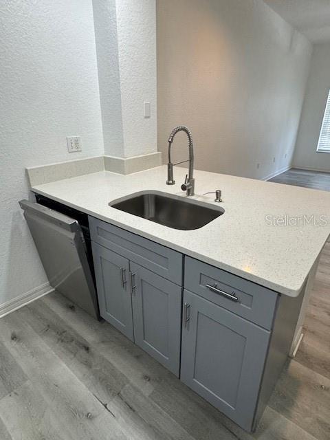A kitchen island features a stainless steel sink, a gooseneck faucet, and gray cabinets — 2222 SAN VITTORINO CIRCLE UNIT 105, KISSIMMEE, FL