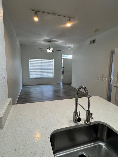 A kitchen sink with a modern faucet overlooks a living area with wood-look flooring — 2222 SAN VITTORINO CIRCLE UNIT 105, KISSIMMEE, FL
