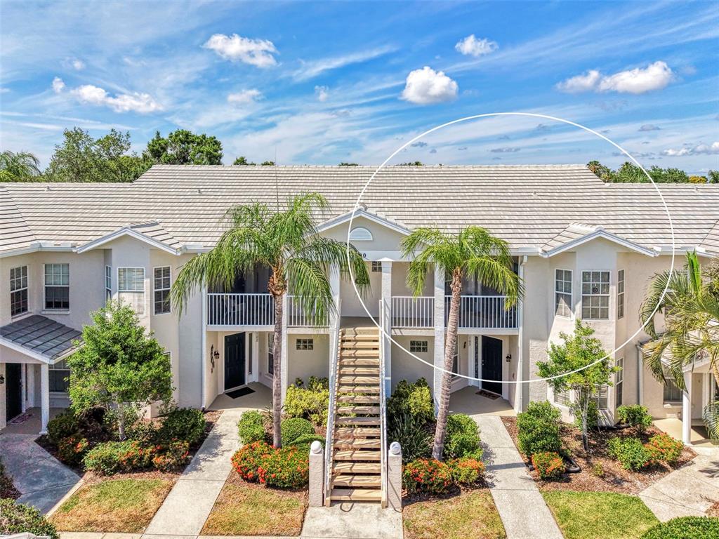 An exterior view of a two-story apartment building with a tiled roof and palm trees — 900 ADDINGTON COURT UNIT 203, VENICE, FL