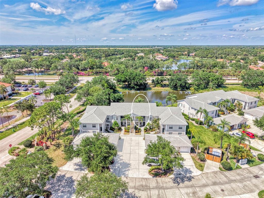 An aerial view of a multi-unit residential building with a tiled roof and surrounding landscaping — 900 ADDINGTON COURT UNIT 203, VENICE, FL