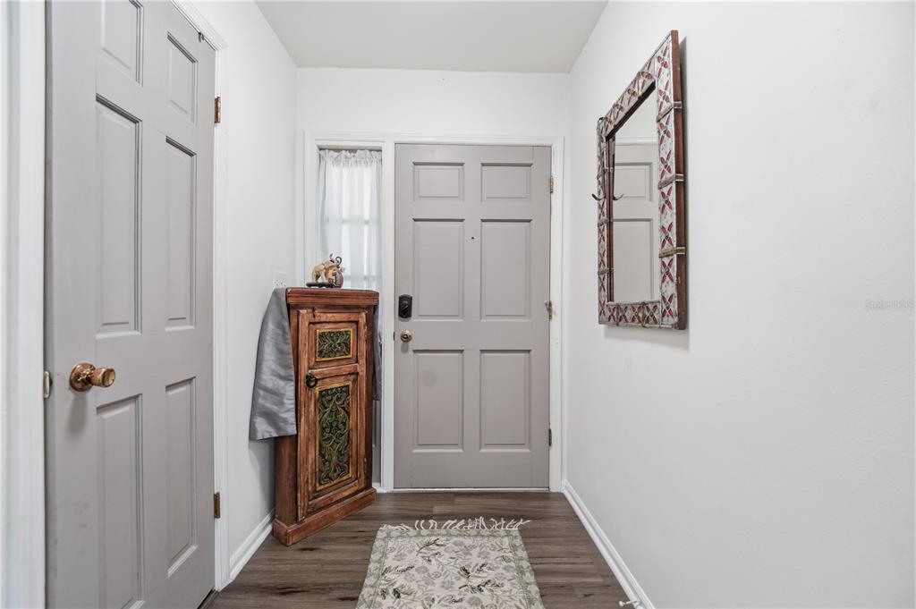 An entryway features a gray front door, wood-look flooring, a decorative cabinet, and a wall mirror — 2680 ROBIN AVENUE, KISSIMMEE, FL