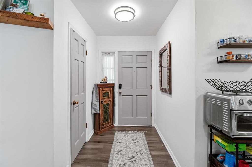 An entryway features a grey front door, a side closet, wood-look flooring, and wall shelving — 2680 ROBIN AVENUE, KISSIMMEE, FL