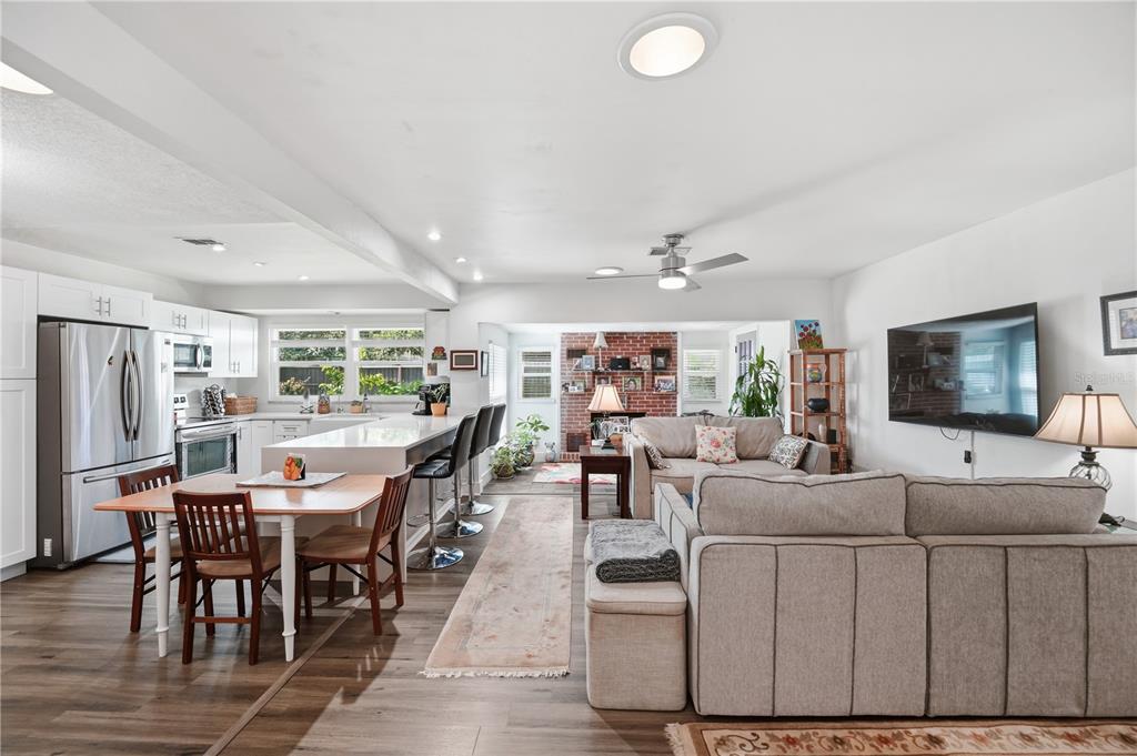 An open-concept kitchen and living area featuring white cabinetry, a kitchen island, and wood flooring — 2680 ROBIN AVENUE, KISSIMMEE, FL