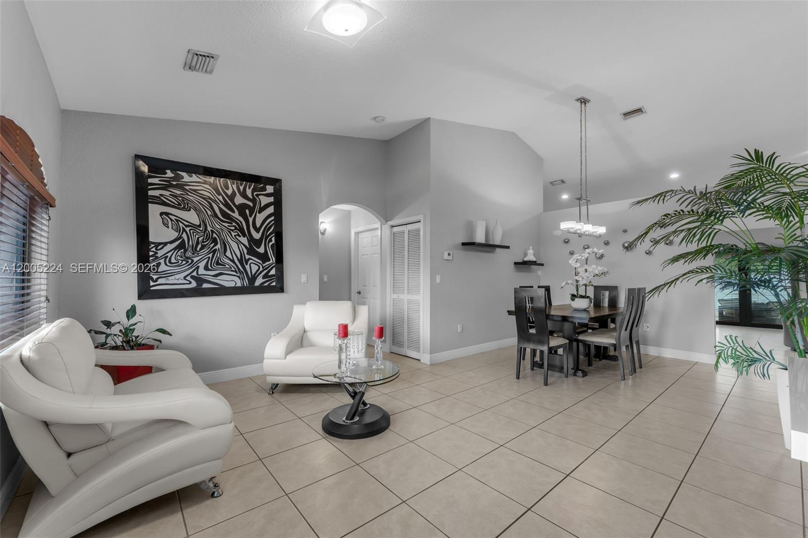 A living and dining area features light tile floors, white leather furniture, and vaulted ceilings — 3160 SW 142nd Ave, Miami FL 33175, MIAMI, FL