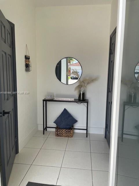 A tiled entryway features a console table, a round wall mirror, and two dark doors — 18214 SW 144th Pl, Miami FL 33177, MIAMI, FL