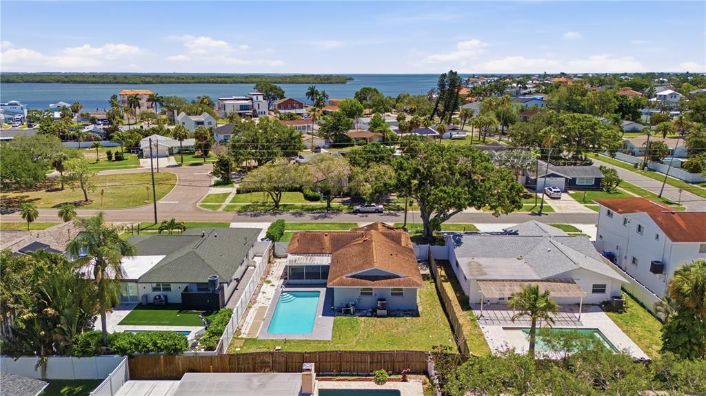 An aerial view shows three residential houses with swimming pools in a coastal neighborhood — 5920 DENVER STREET NE, ST PETERSBURG, FL