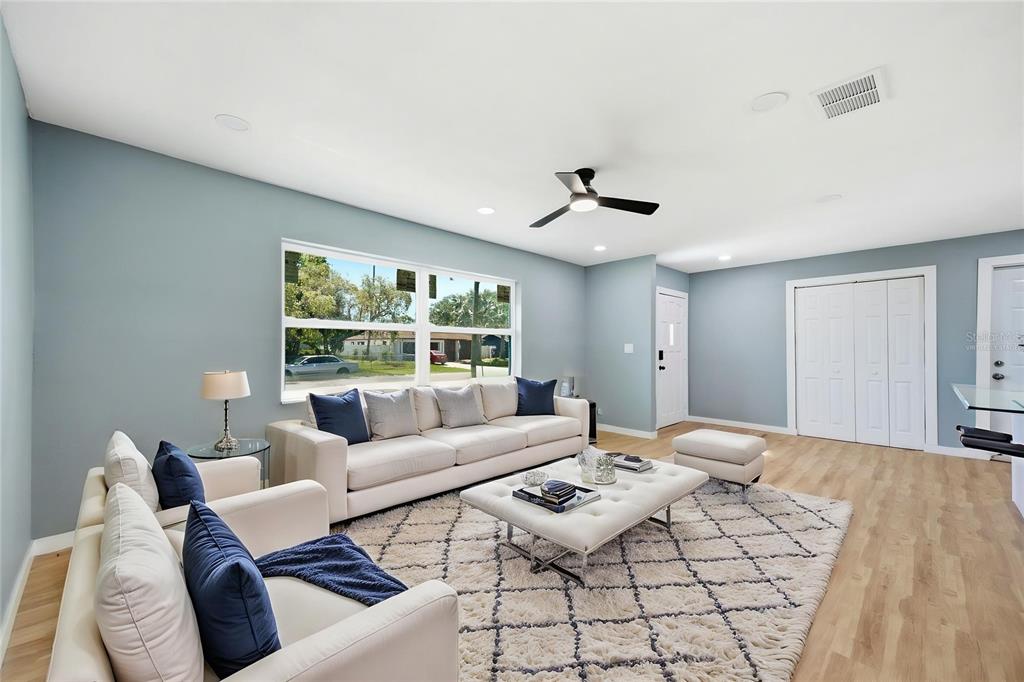 A living room features light blue walls, a white sofa, a rug, and a ceiling fan — 5920 DENVER STREET NE, ST PETERSBURG, FL