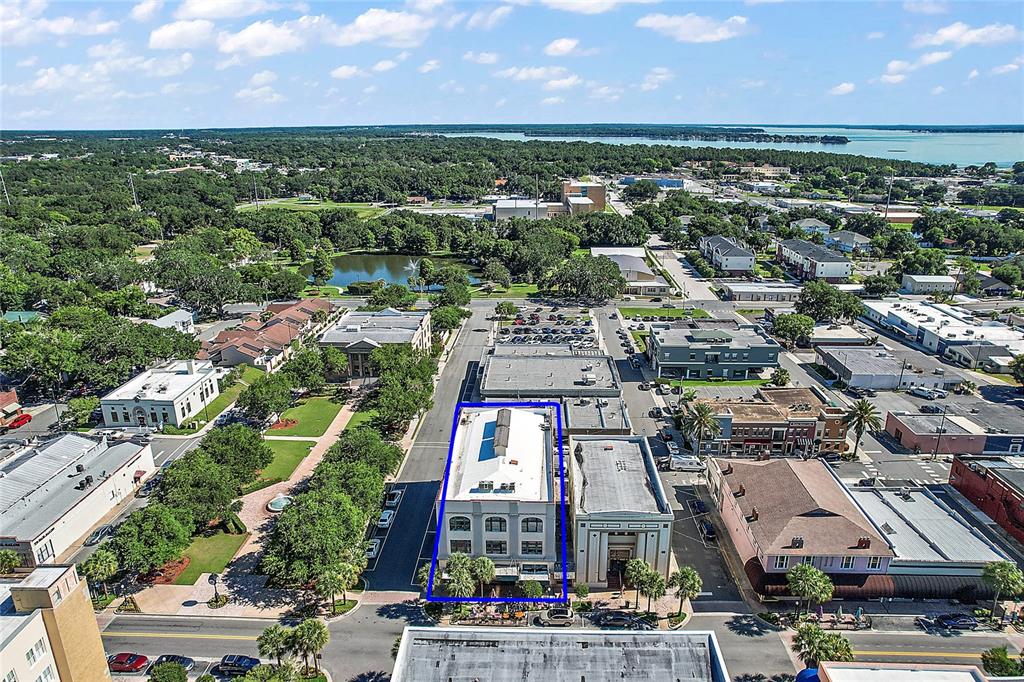 An aerial view shows a multi-story building highlighted in blue within a suburban town center — 410 W MAIN STREET, LEESBURG, FL
