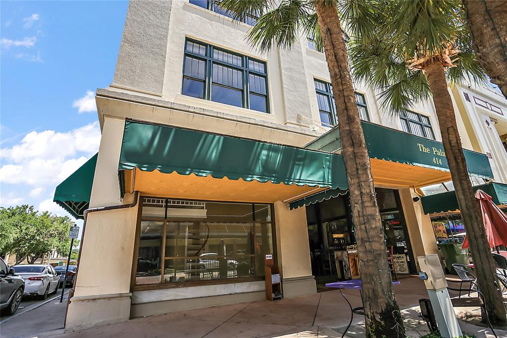 The exterior of a multi-story building features a green awning, large windows, and palm trees — 410 W MAIN STREET, LEESBURG, FL