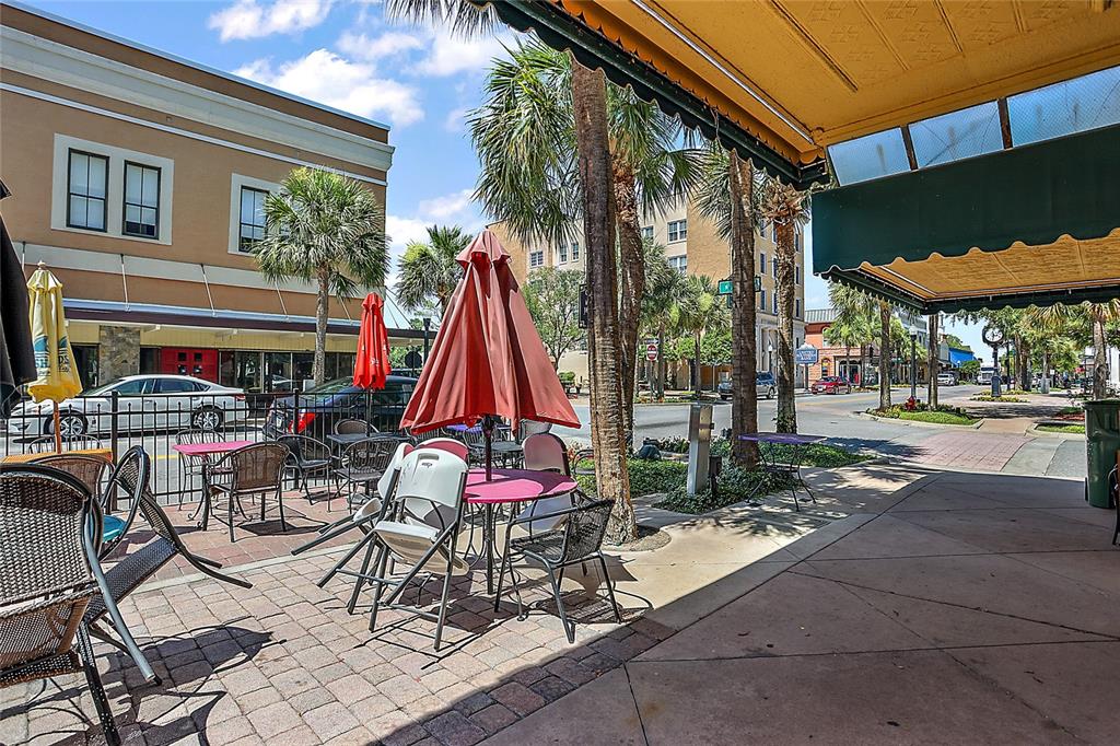 An outdoor patio area features tables with umbrellas and chairs on a brick-paved surface — 410 W MAIN STREET, LEESBURG, FL