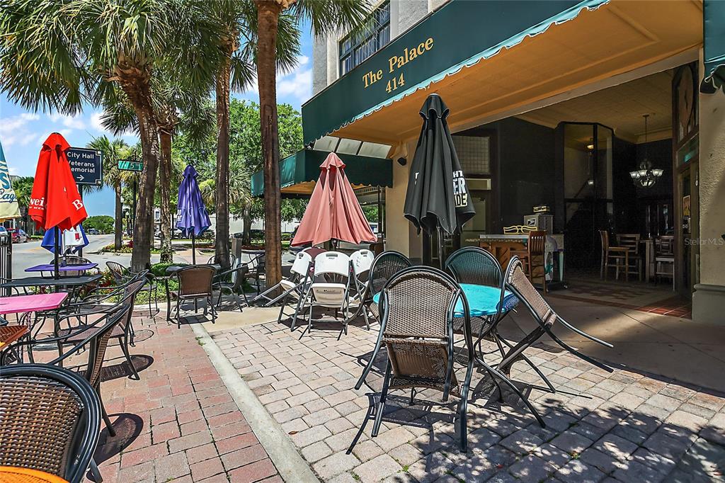 An outdoor patio area features tables, chairs, and umbrellas in front of a building entrance — 410 W MAIN STREET, LEESBURG, FL