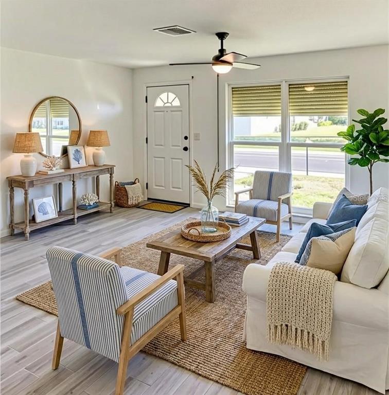 A bright living room features a white sofa, striped armchairs, wood furniture, and a rug — 4318 GREAT LAKES DRIVE N, CLEARWATER, FL