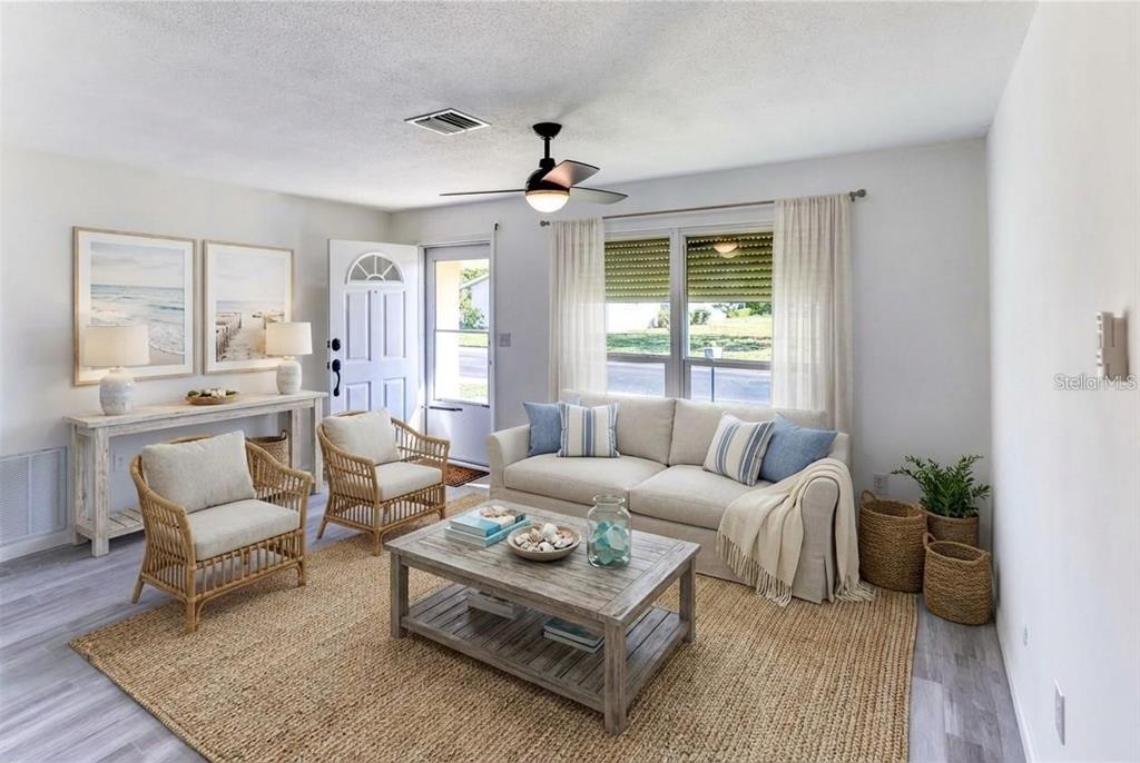 A living room features a beige sofa, two rattan chairs, a coffee table, and area rug — 4318 GREAT LAKES DRIVE N, CLEARWATER, FL