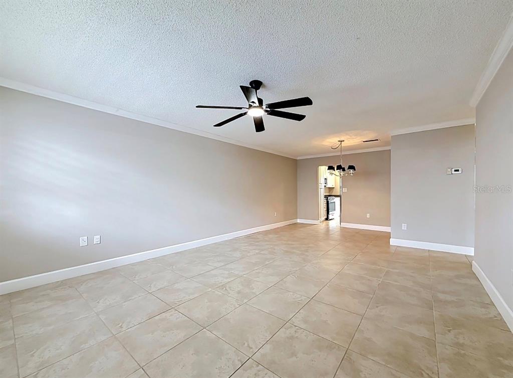 An open living area features light-colored tile flooring, a ceiling fan, and neutral walls — 6025 SHORE BOULEVARD S UNIT 106, GULFPORT, FL