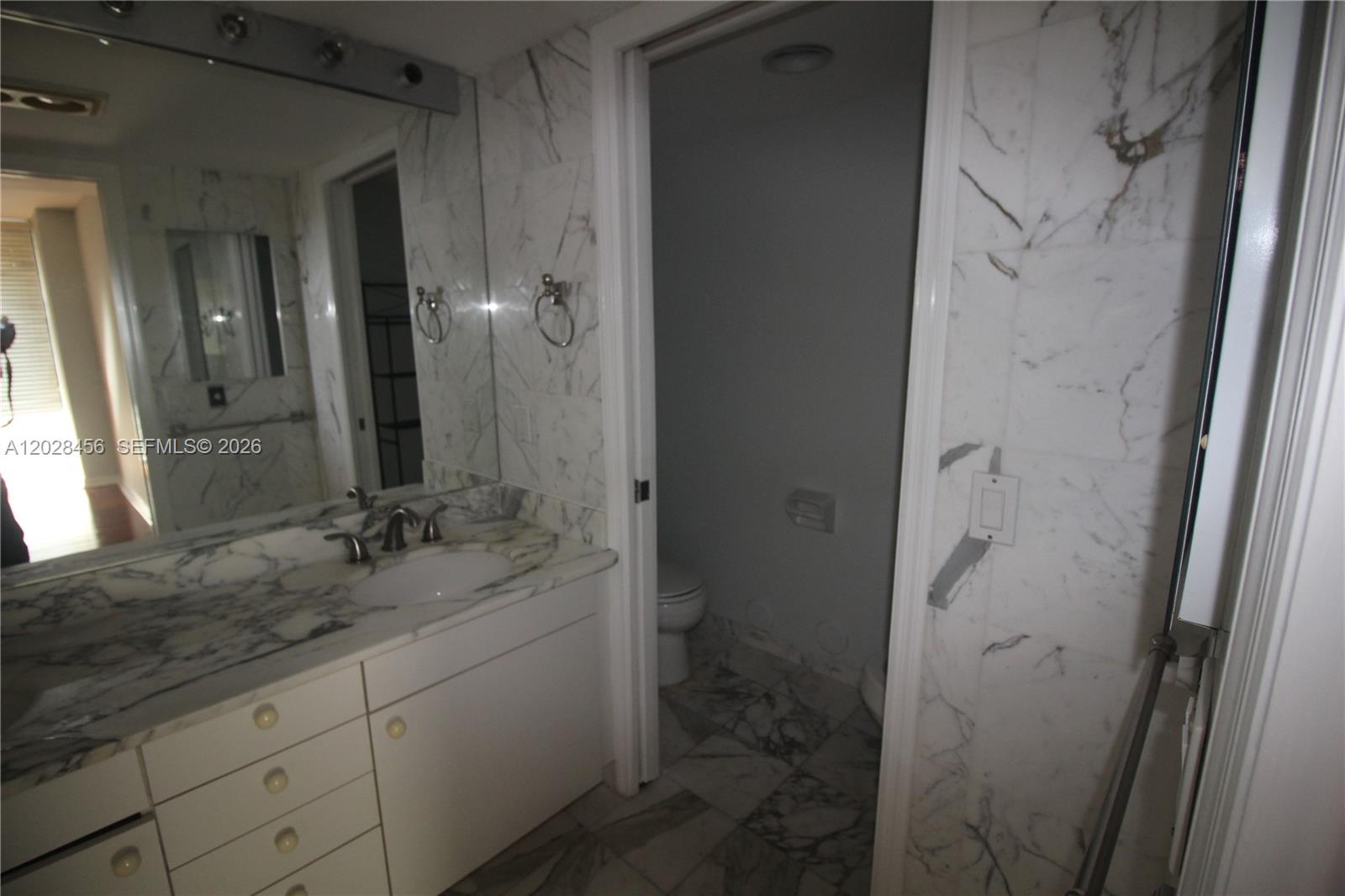 A bathroom features a marble vanity, a large mirror, and a separate toilet area — 441 Valencia Ave # 202, Coral Gables FL 33134, CORAL GABLES, FL