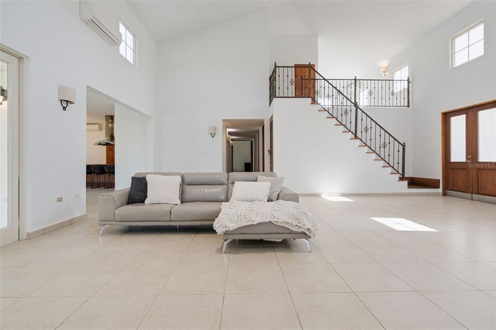 A spacious living room features white walls, tile flooring, a gray sectional sofa, and stairs — 451 CAMINO GUAJATACA, DORADO, PR