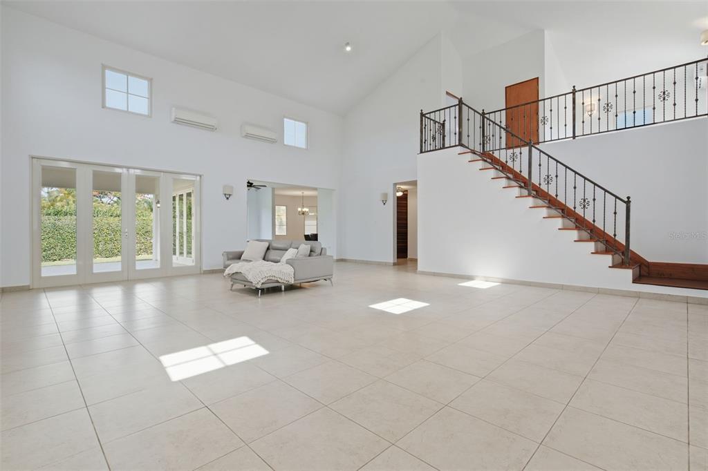 A spacious living room features white tile floors, a vaulted ceiling, and a wooden staircase — 451 CAMINO GUAJATACA, DORADO, PR