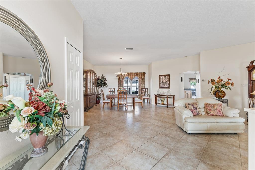 A spacious open-concept living and dining area features tile flooring, neutral walls, and traditional furniture — 16 LONDON DRIVE, PALM COAST, FL