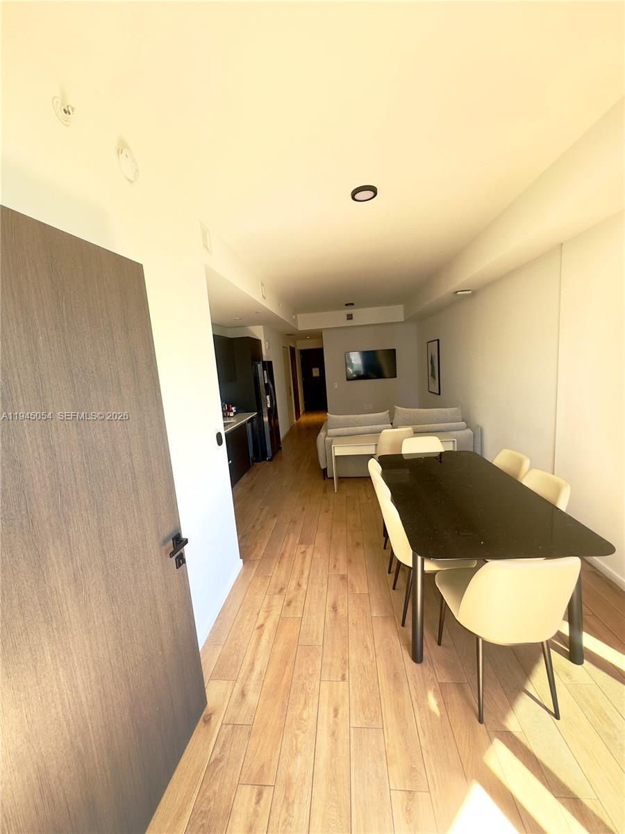 A modern apartment interior features a dining area with a black table and light-colored chairs — 398 NE 5th St # 2114, Miami FL 33132, MIAMI, FL