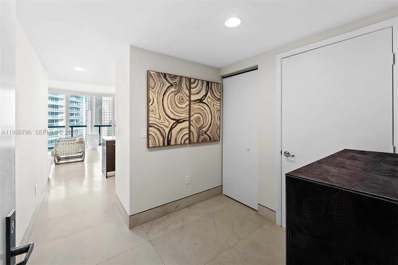 An interior hallway features light tile flooring, two abstract wall art pieces, and white doors — 495 Brickell Ave # 2904, Miami FL 33131, MIAMI, FL