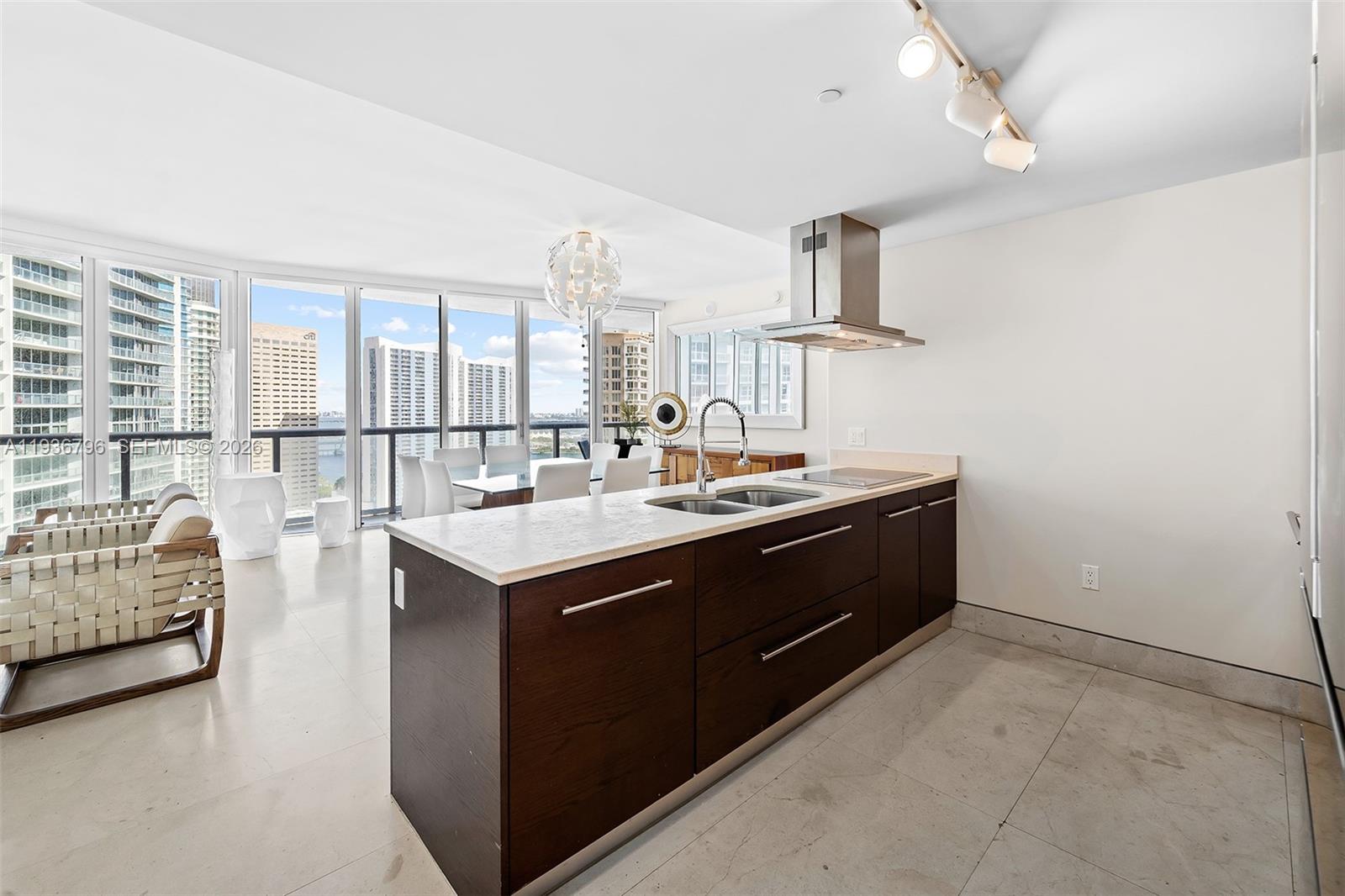 A modern kitchen features dark wood cabinetry, a white stone island, and floor-to-ceiling windows — 495 Brickell Ave # 2904, Miami FL 33131, MIAMI, FL