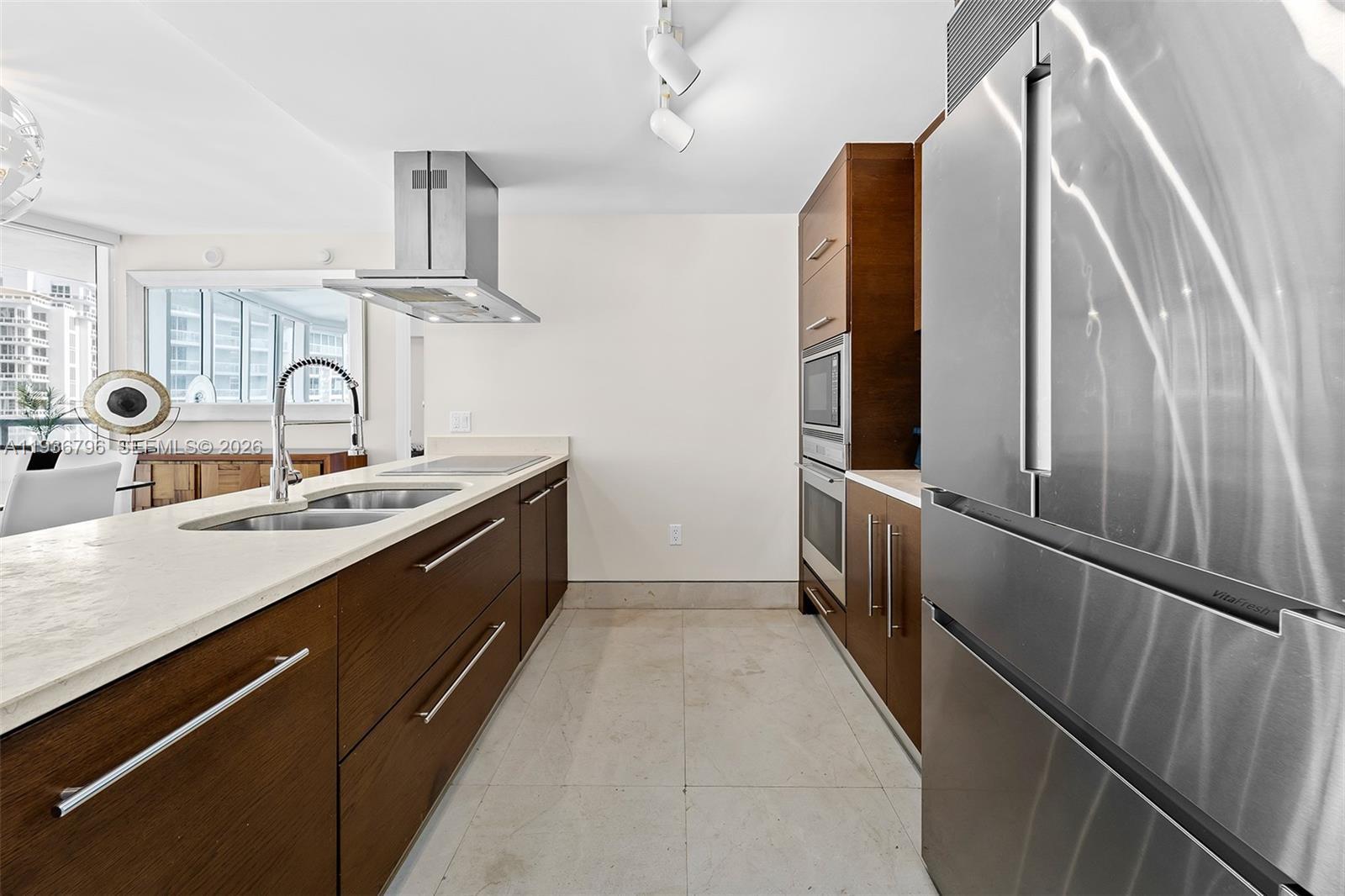 A modern kitchen features dark wood cabinetry, stainless steel appliances, and a light-colored stone countertop — 495 Brickell Ave # 2904, Miami FL 33131, MIAMI, FL