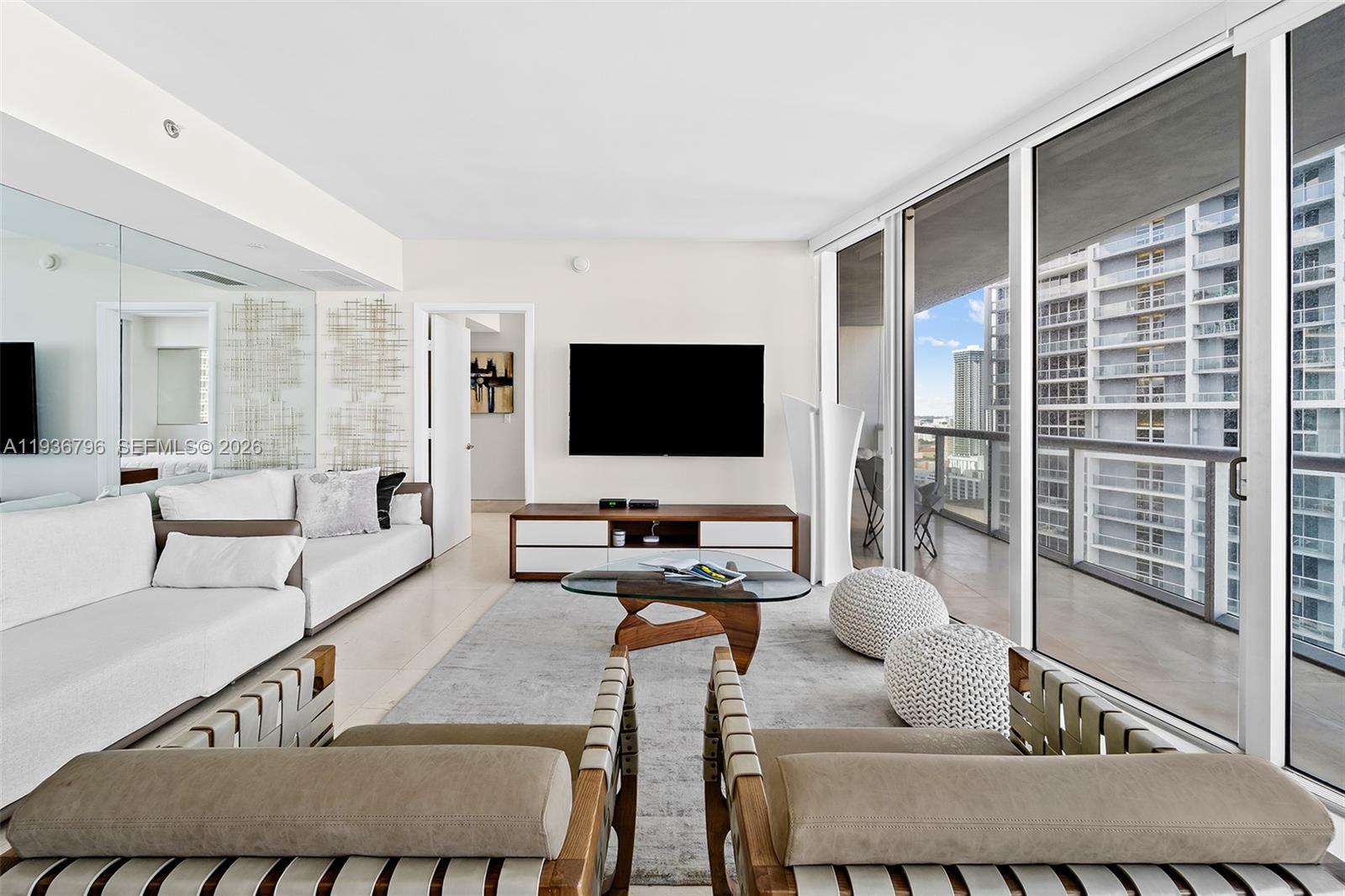 A modern living room features a white sofa, two leather chairs, and a balcony view — 495 Brickell Ave # 2904, Miami FL 33131, MIAMI, FL