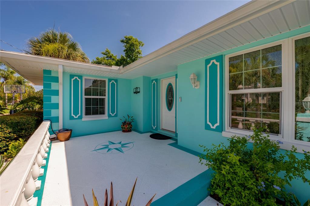 A bright turquoise house exterior features a white porch with a painted compass rose design — 697 JOHN ANDERSON DRIVE, ORMOND BEACH, FL