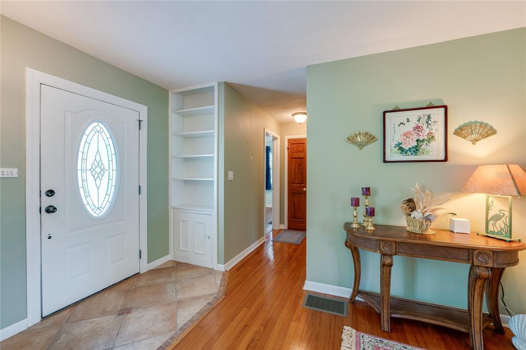 An entryway features a white front door, built-in shelving, hardwood floors, and a console table — 697 JOHN ANDERSON DRIVE, ORMOND BEACH, FL