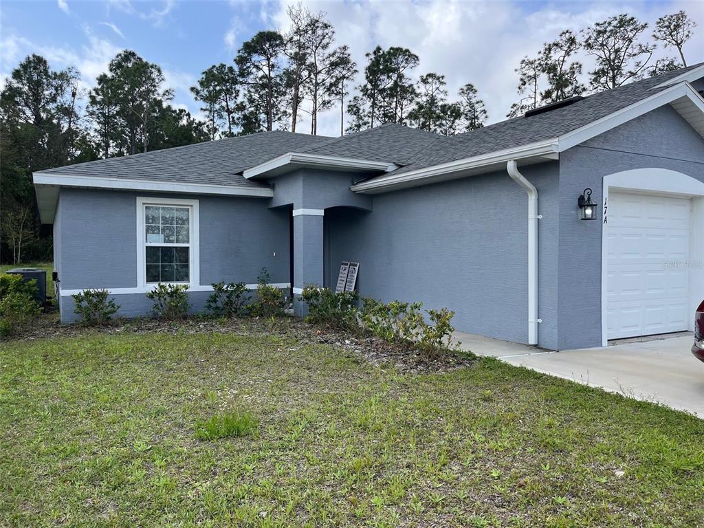 A single-story blue house with a white garage door and a front yard — 17 FRENEAU LANE UNIT A&B, PALM COAST, FL