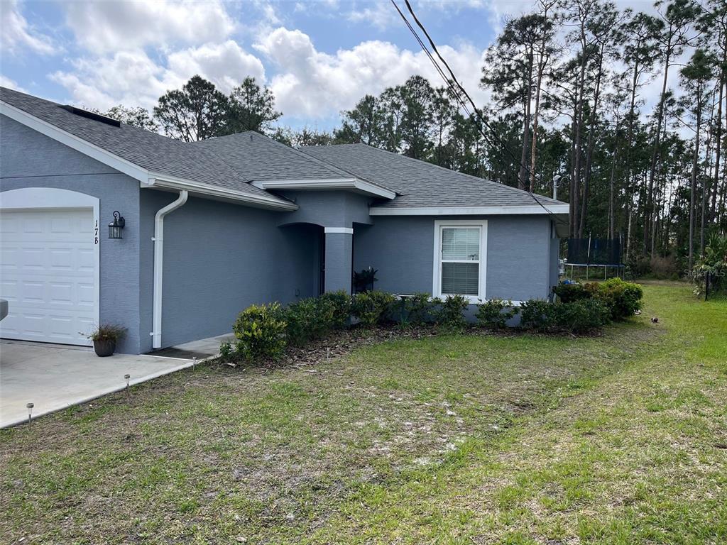 A gray, single-story house with a white garage door and a small front yard — 17 FRENEAU LANE UNIT A&B, PALM COAST, FL