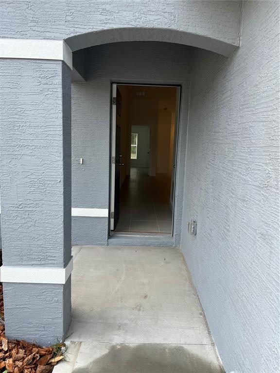 A gray stucco exterior entryway leads to an open front door revealing a tiled interior — 17 FRENEAU LANE UNIT A&B, PALM COAST, FL