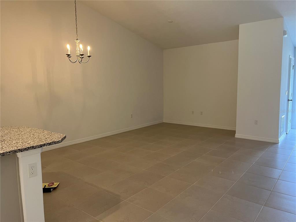 An open dining area features beige tile flooring, white walls, and a hanging chandelier — 17 FRENEAU LANE UNIT A&B, PALM COAST, FL