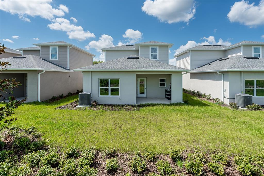 The rear exterior of a two-story house features a covered patio and central window — 5347 VISTA LAGO DRIVE, ORLANDO, FL