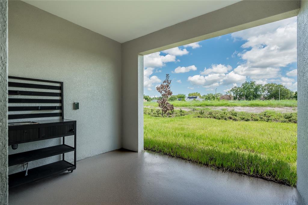 A covered patio features a black metal storage cart and an open view of grass — 5347 VISTA LAGO DRIVE, ORLANDO, FL