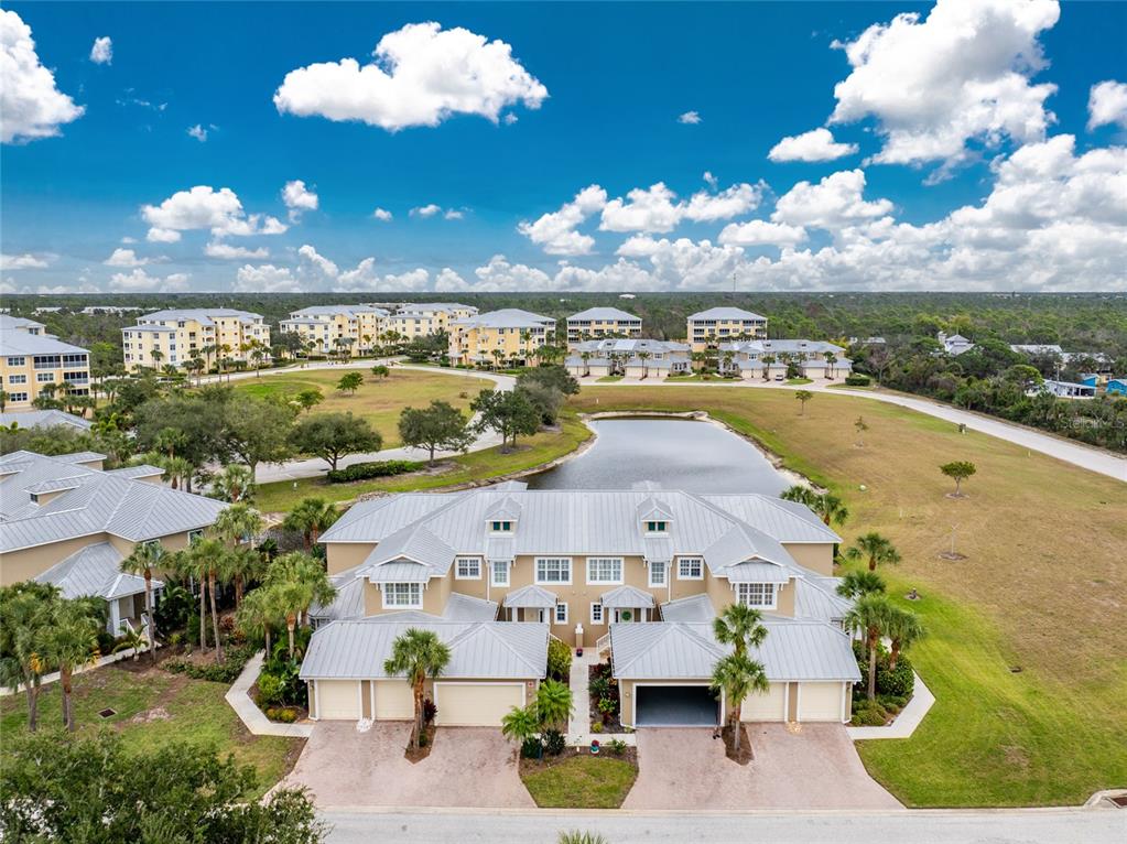 An aerial view of a multi-unit residential building with a pond and surrounding landscape — 10641 LEMON CREEK LOOP UNIT 102, ENGLEWOOD, FL