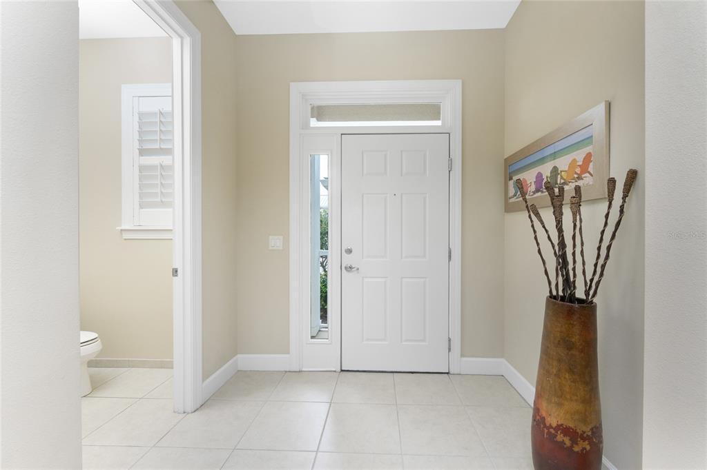 An entryway features a white front door, tiled flooring, and a decorative vase with branches — 10641 LEMON CREEK LOOP UNIT 102, ENGLEWOOD, FL