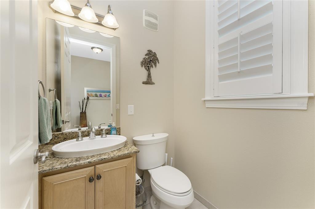 A bathroom features a granite vanity, a white toilet, and a window with plantation shutters — 10641 LEMON CREEK LOOP UNIT 102, ENGLEWOOD, FL