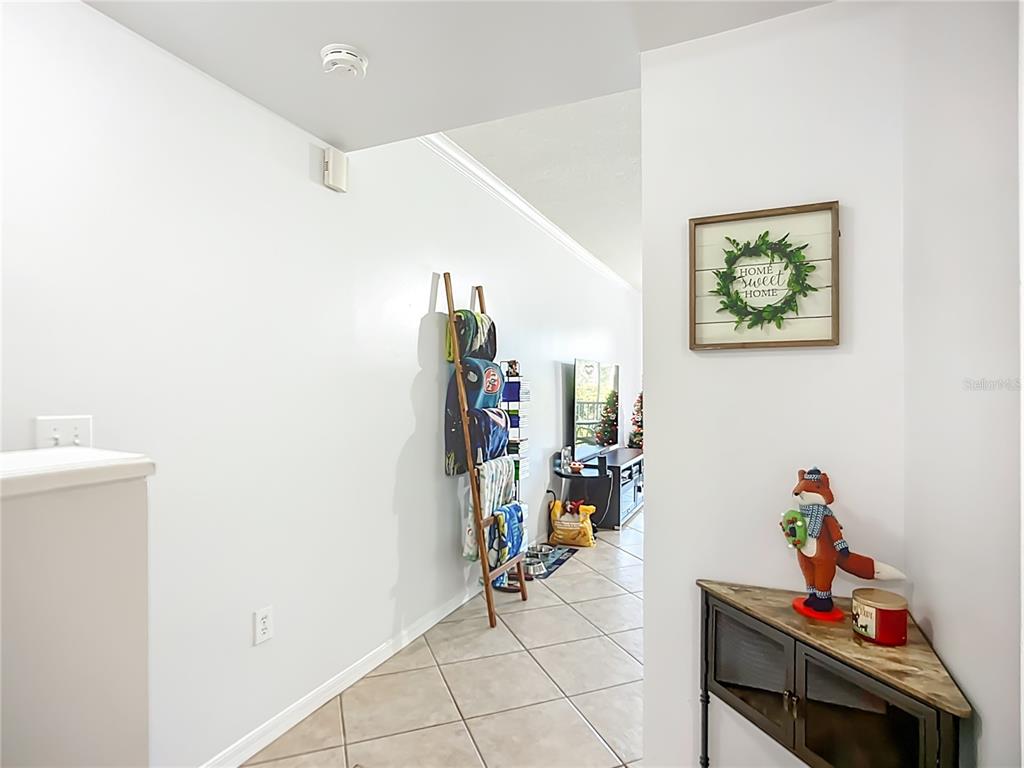 A hallway with tile flooring leads to a living area featuring a blanket ladder — 4990 BARALDI CIRCLE UNIT 209, SARASOTA, FL