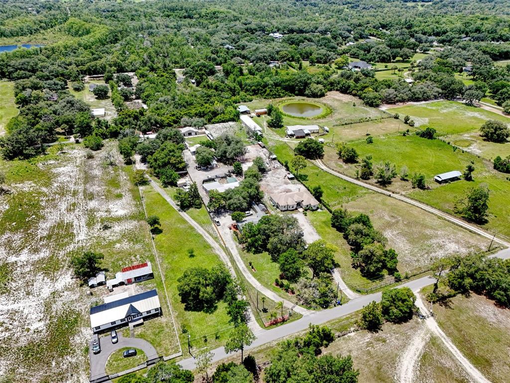 An aerial view shows a rural property with multiple buildings, a pond, and surrounding trees — 2036 LAKE VIEW AVENUE, CHULUOTA, FL