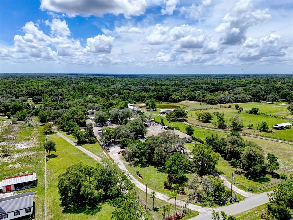 An aerial view shows a rural property with multiple buildings, trees, and fenced pastures — 2036 LAKE VIEW AVENUE, CHULUOTA, FL