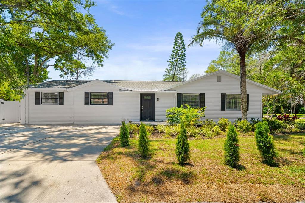 A single-story white house with a dark front door and a concrete driveway — 2118 S VENUS STREET, TAMPA, FL