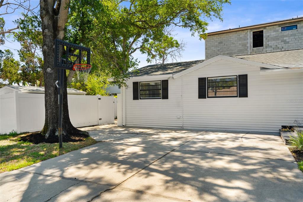A white house exterior features a concrete driveway, a basketball hoop, and a fenced yard — 2118 S VENUS STREET, TAMPA, FL