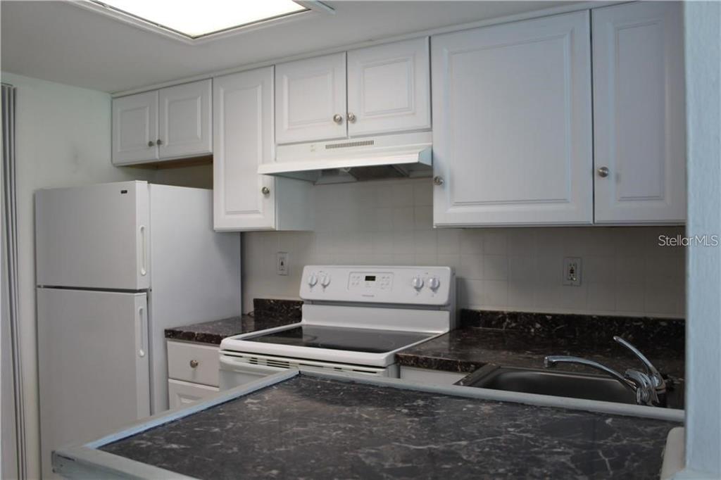 A kitchen features white cabinets, dark laminate countertops, and white appliances — 3832 N LAKE DRIVE UNIT 116, TAMPA, FL